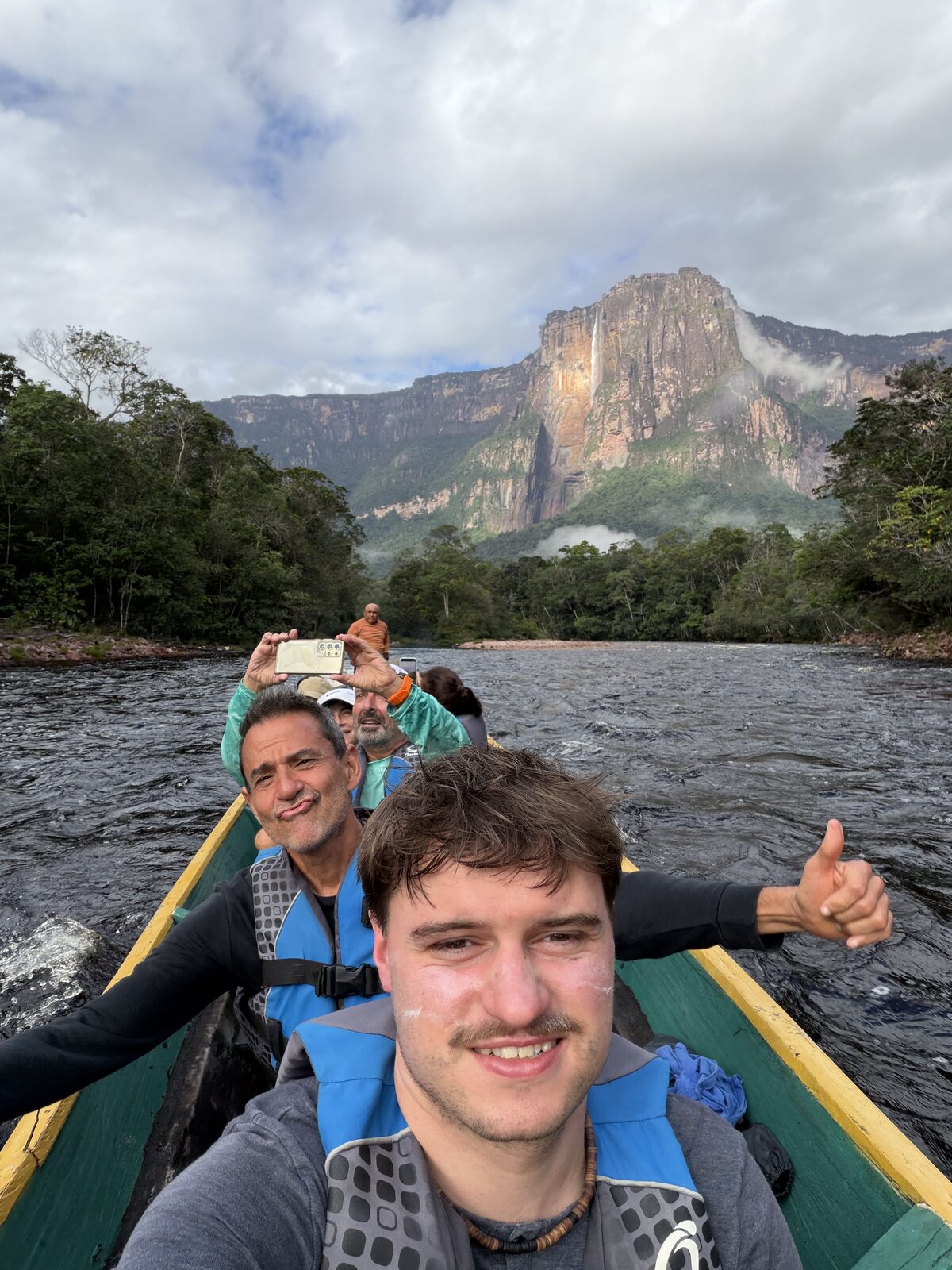 Benito traveling by river with local friends and a tepui behind them in Canaima